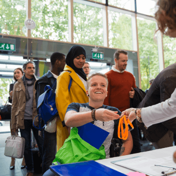 Smiling woman in wheelchair arriving and checking in at conference registration table