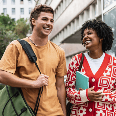 Two university students laughing while walking on campus.