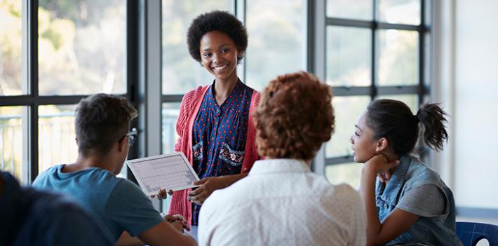 A woman presenting information to a group of three people.
