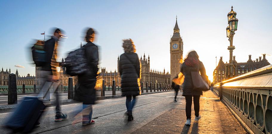 A group of people walking across a bridge in London.