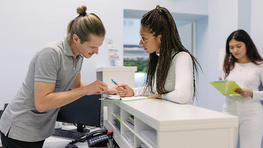 A female visitor filling in a document at a reception desk.