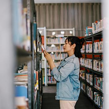 A female researcher looking at a book in a library.