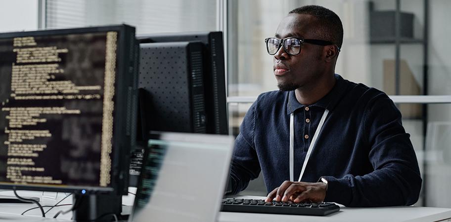 A male computer technician working at a desktop.