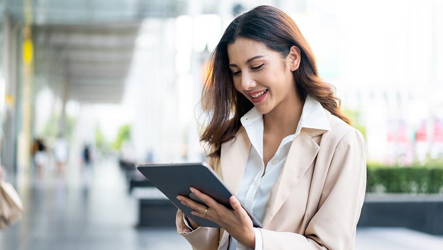 A smiling woman looking at a tablet.