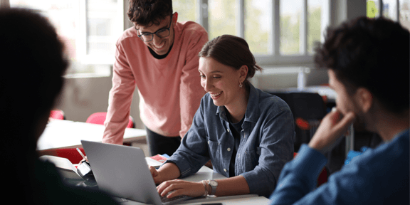 A group of students working together around a table in class at college.