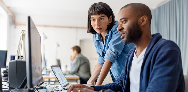 Two business people looking at desktop computer monitor.