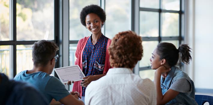 A woman presenting information to a group of three people.