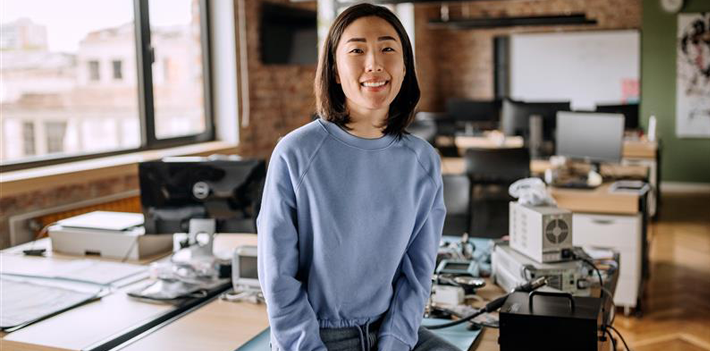 A person sitting on a desk in an office environment.