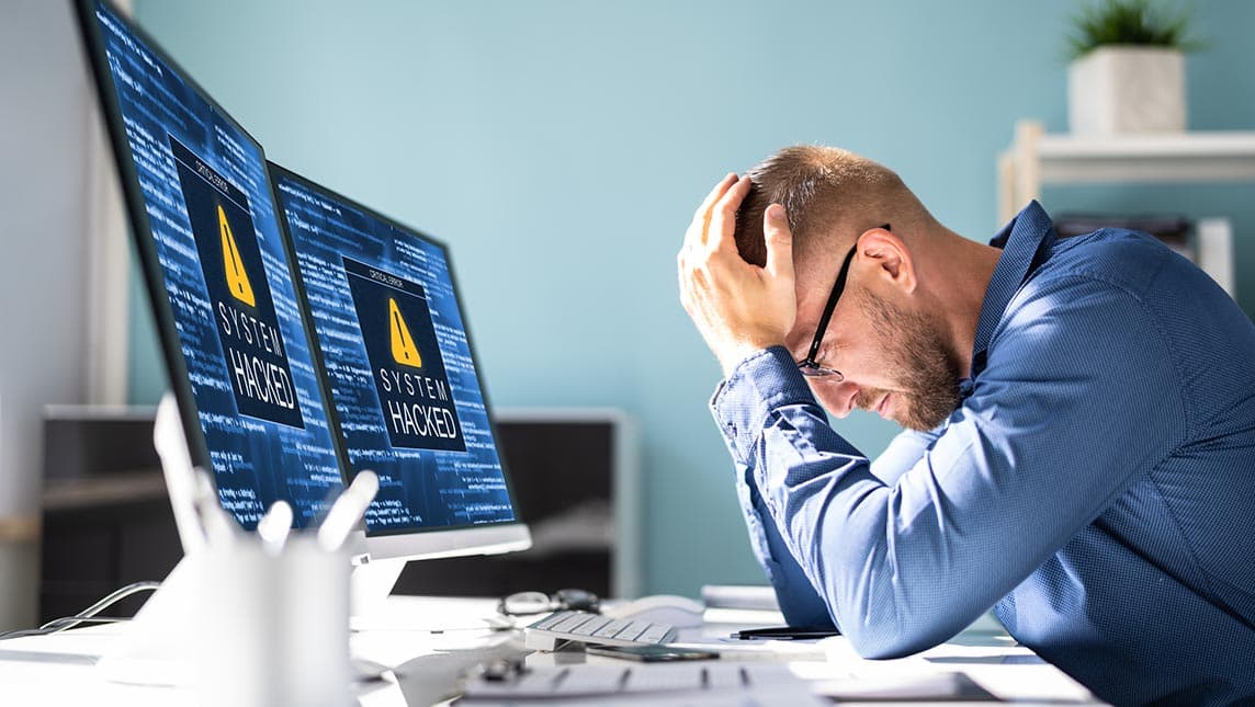 Man sitting at a desk holding head in hands