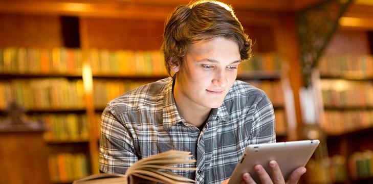 A person in a library looks at a tablet screen.