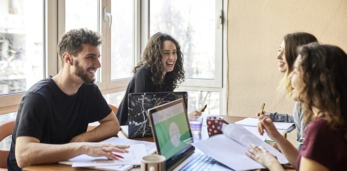 Students sitting at a table with laptops
