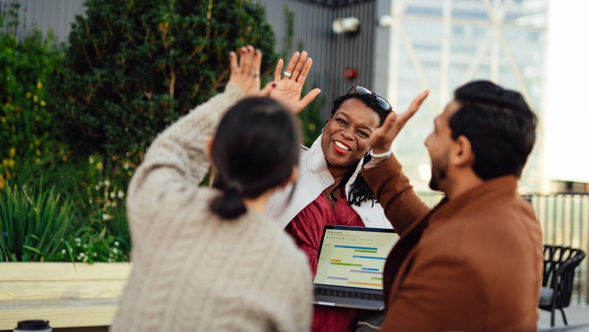 Three coworkers giving each other a high five