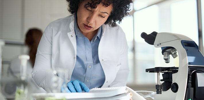A researcher reads a paper in a lab.