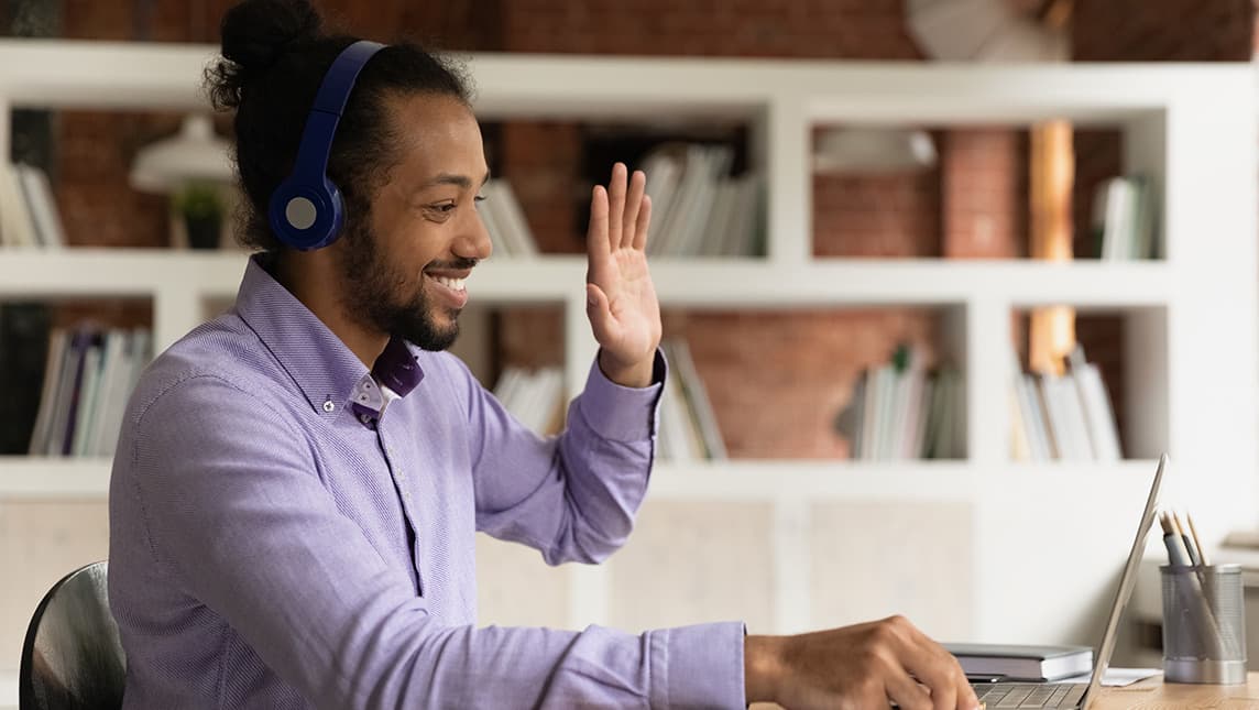A student waves at his web camera to introduce himself during a virtual study session.