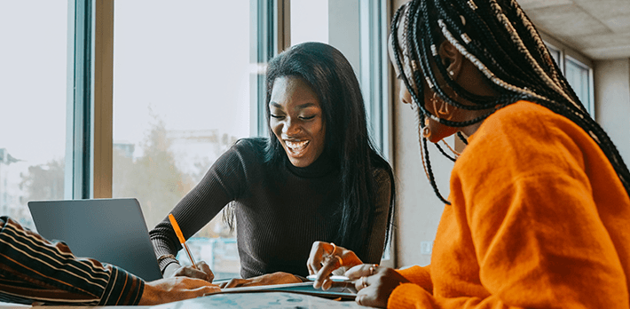 Two students smile as they study at their computer.