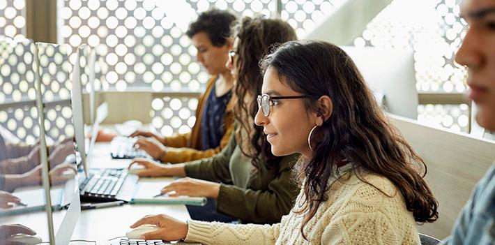 Students sitting at a table with computers