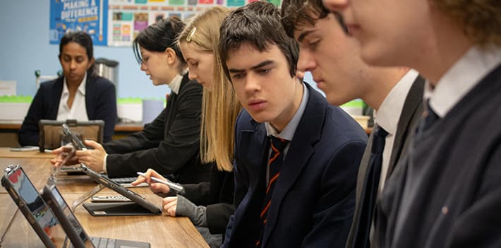 School pupils working on laptops in a classroom.
