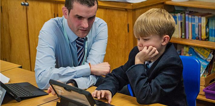 Male teacher and student looking at a laptop.