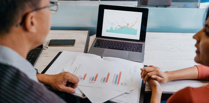 Work colleagues examine data on a screen.