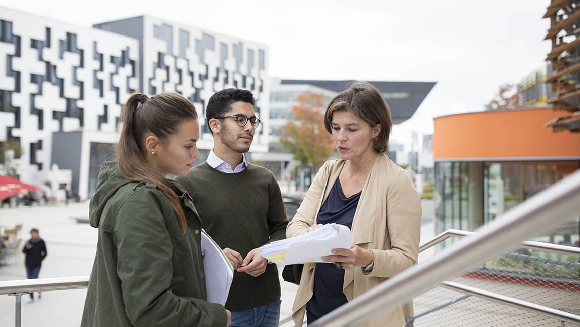Three members of staff meeting on a campus.