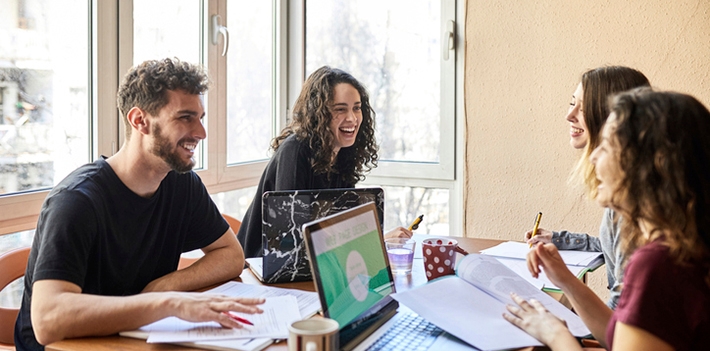Four friends sitting at a table with a laptop.