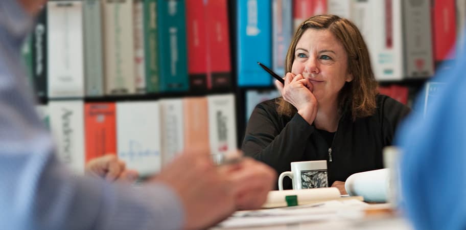 A female librarian sitting at a table in a library.